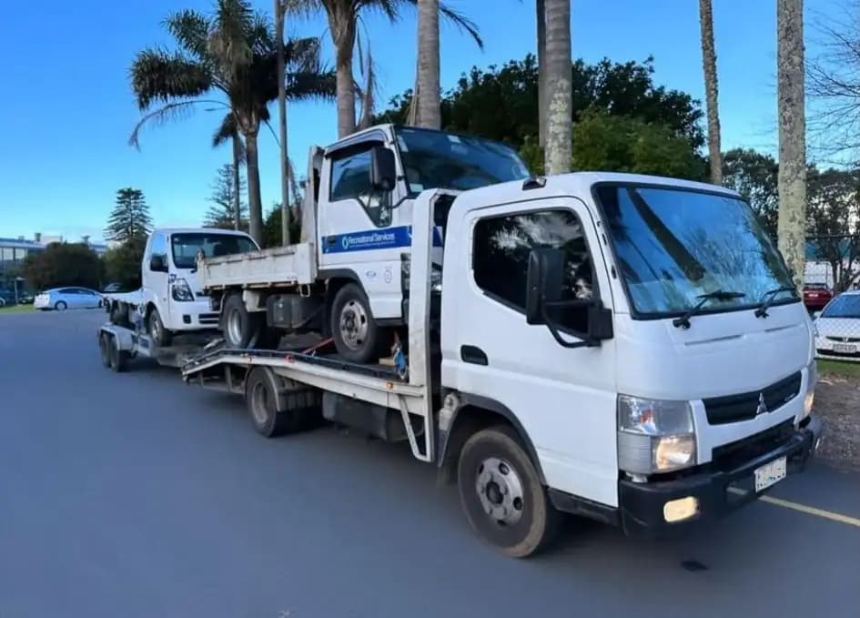 A used flatbed truck being loaded onto an Apex Car Removal tow truck in the Waikato region