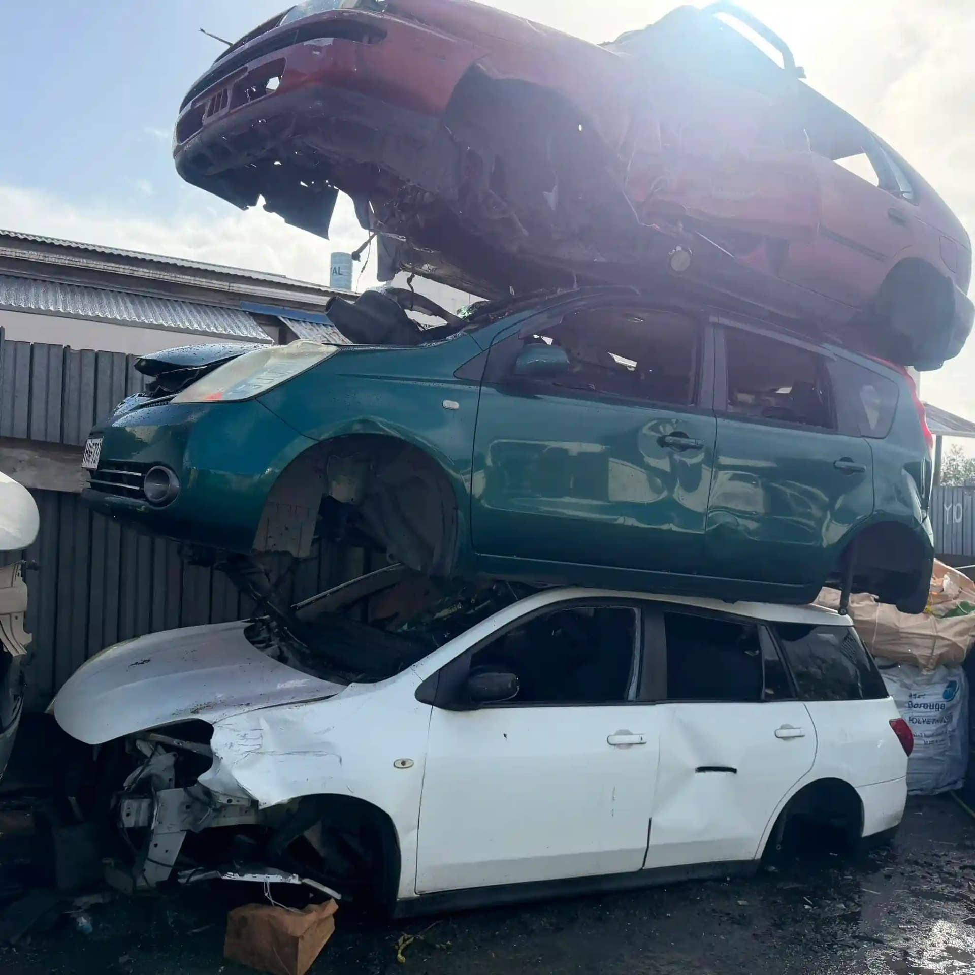 Apex Car Removal flatbed tow truck loading an old sedan on a residential street in Rotorua with Lake Rotorua in the background